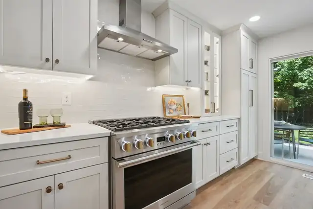 Bexley, OH kitchen with white cabinets, stainless Monogram range and chimney hood, white subway tile and patio door