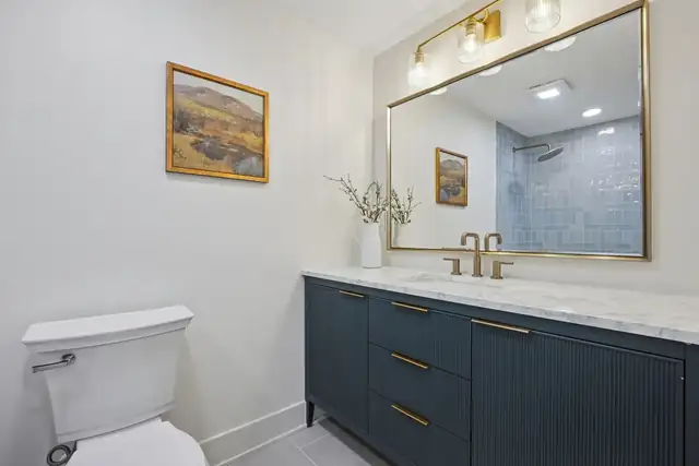 Columbus, OH bathroom remodel with navy fluted vanity, brass fixtures, marble countertop and gold framed mirror