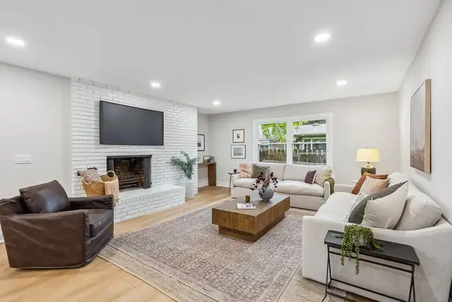 Columbus, OH living room refresh with painted white brick fireplace, wall-mounted TV, light wood floors and new lighting