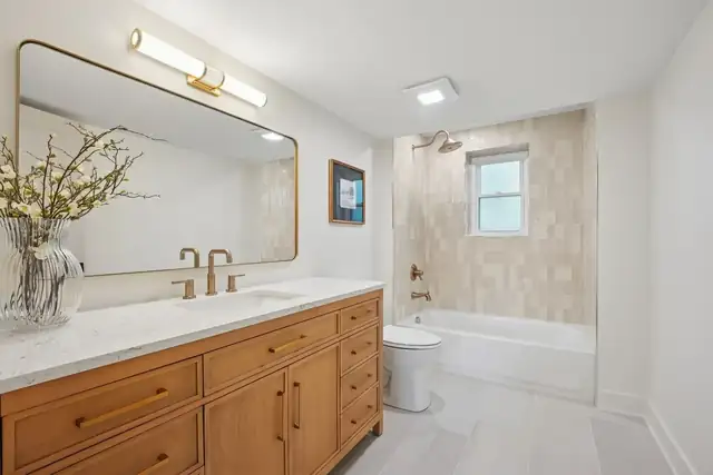 Upper Arlington, OH basement bathroom added with wood vanity, marble-look top, brass faucet and tiled tub shower